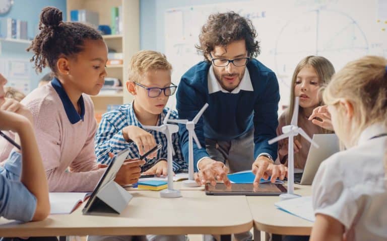 Teacher Holding Tablet Computer Explains Lesson