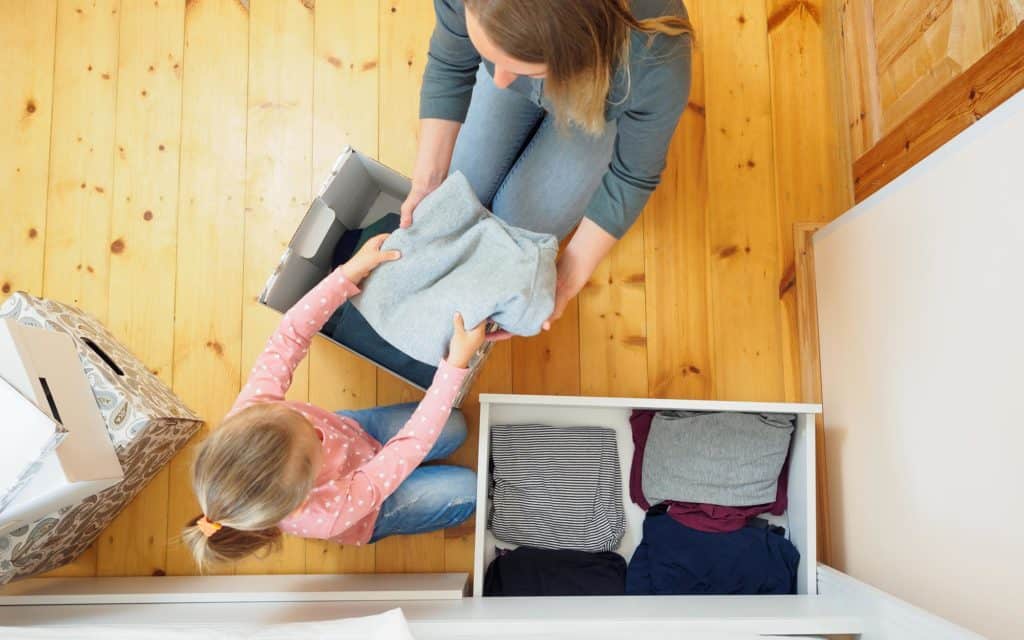 Parent with child organizing clothes in drawer