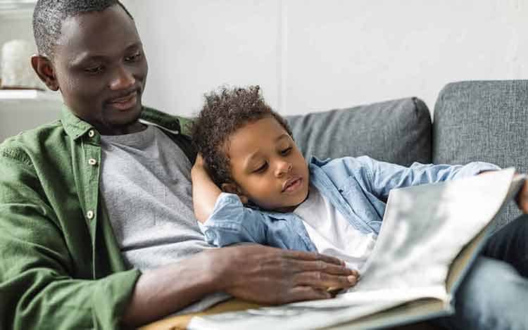 A-parent-and-child-on-couch-reading-a-book-together