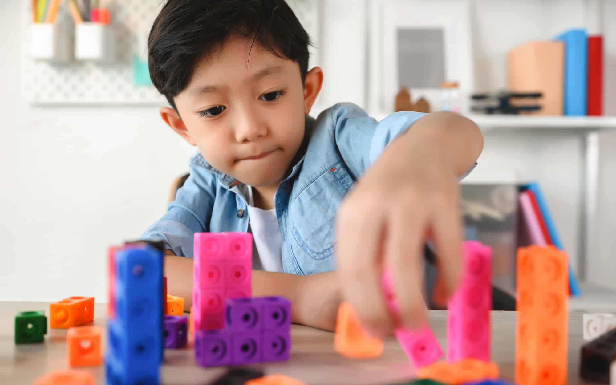 Child Playing Colorful Plastic Cubes on Desk at Home