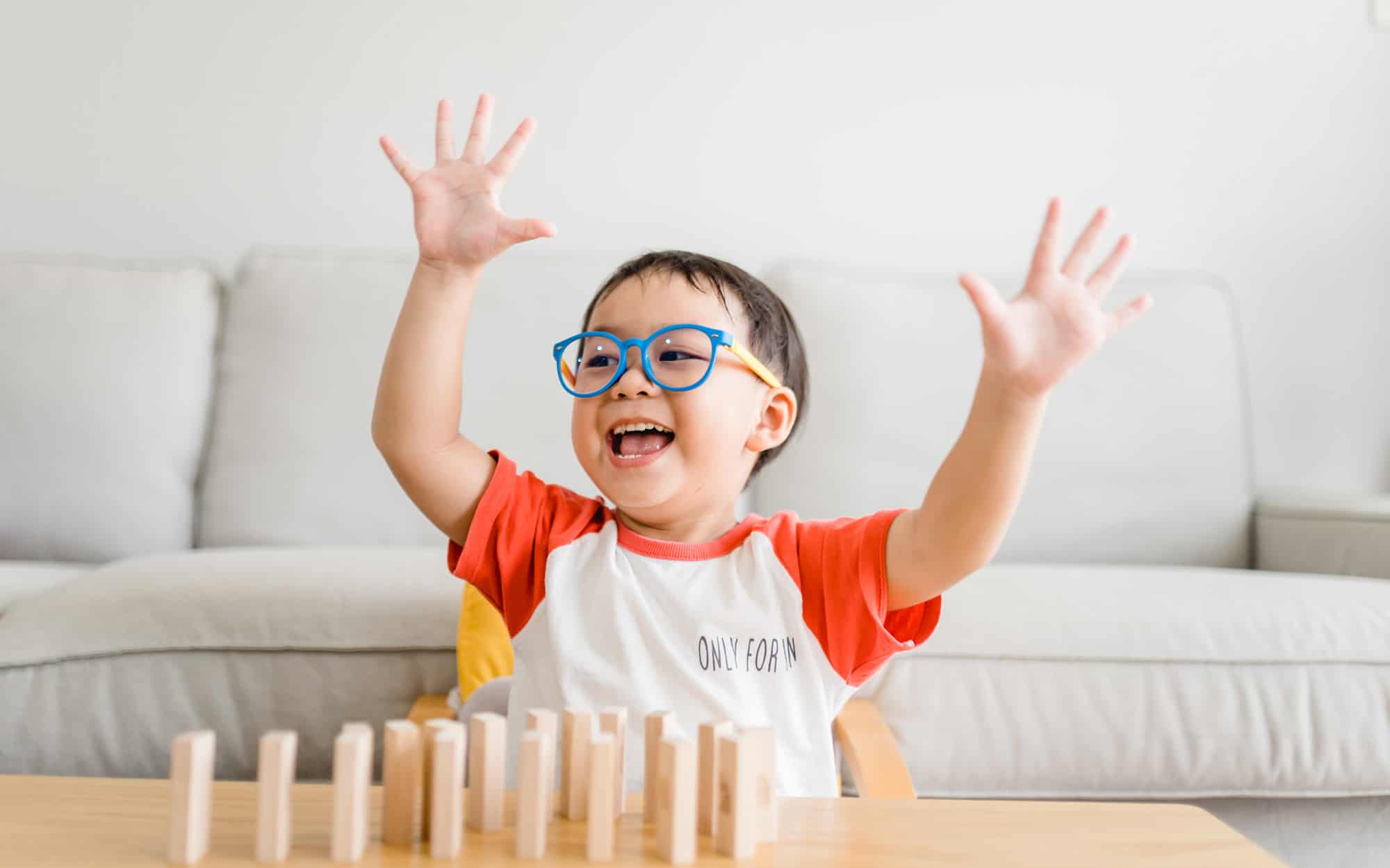 toddler boy raised hand wooden toy block at home