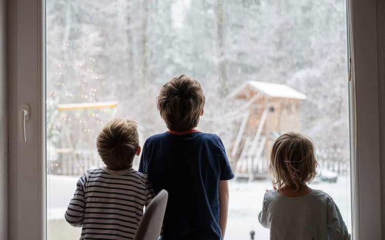 Kids looking out the window while snowing
