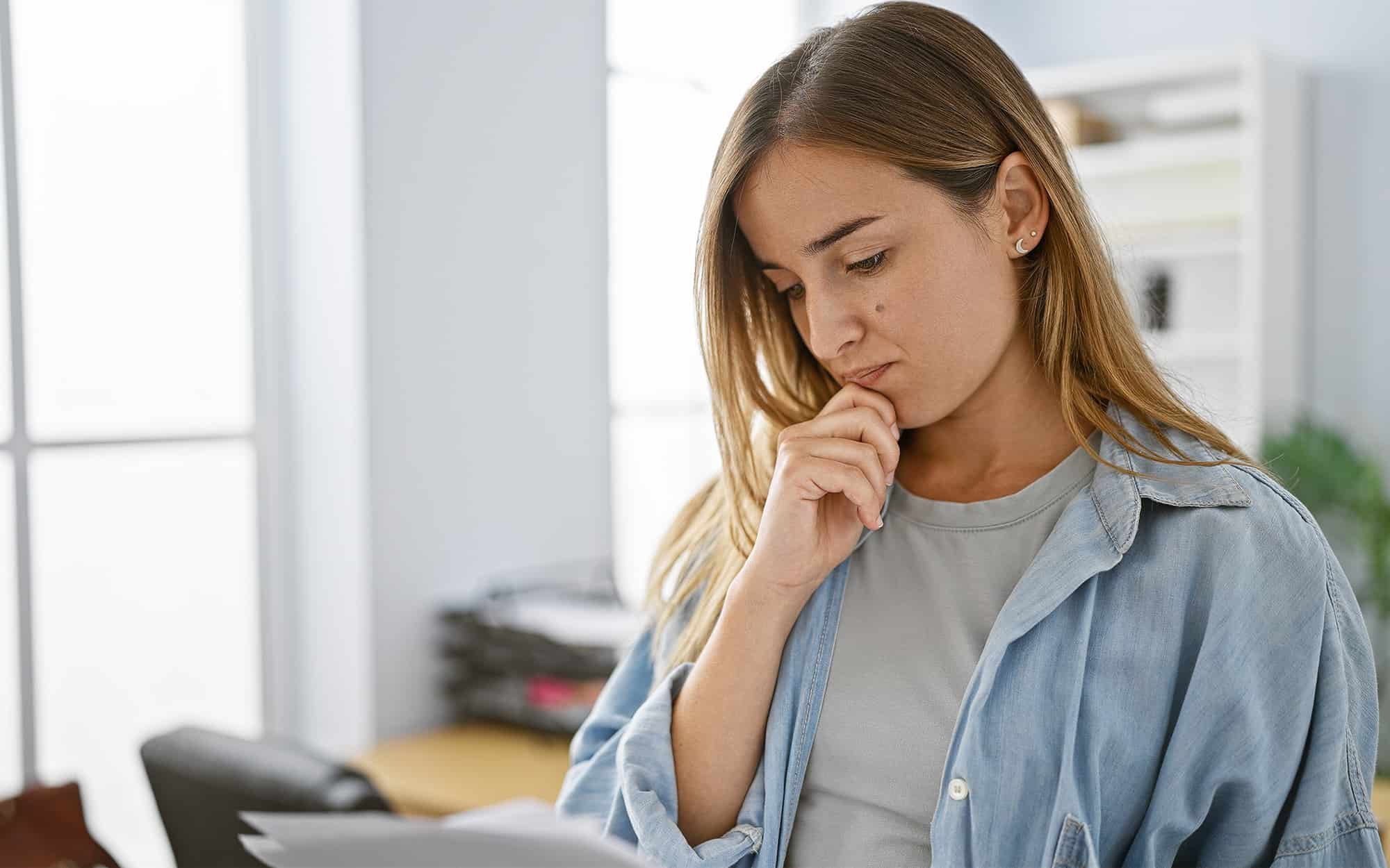 Worried yet focused blonde business woman worker engrossed in reading document