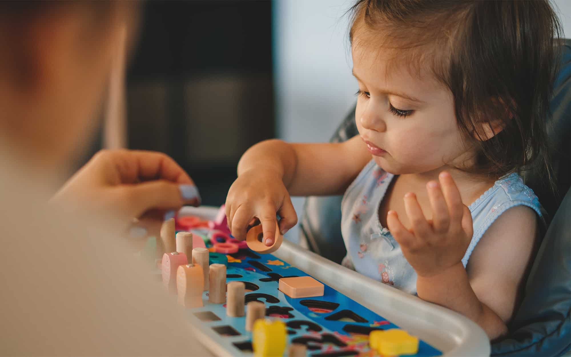 Side view of a little girl playing with wooden blocks